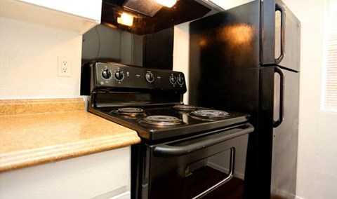 A black stove and refrigerator in a kitchen.