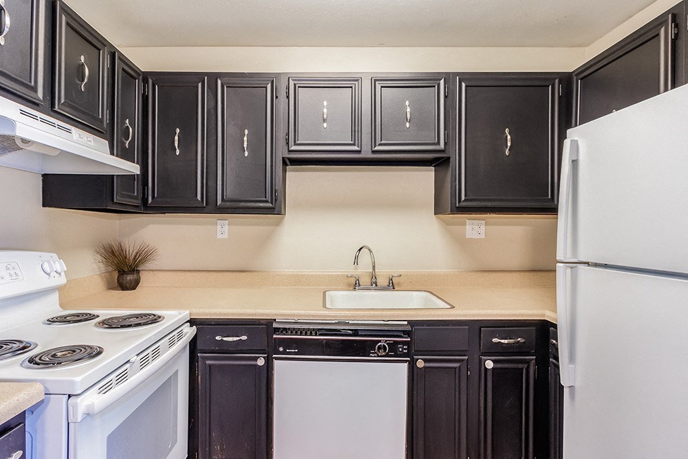 A kitchen with black cabinets and white appliances.