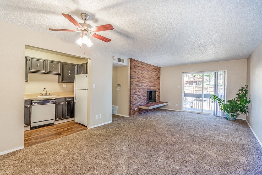 A living room with a fireplace and a kitchen area in the background.