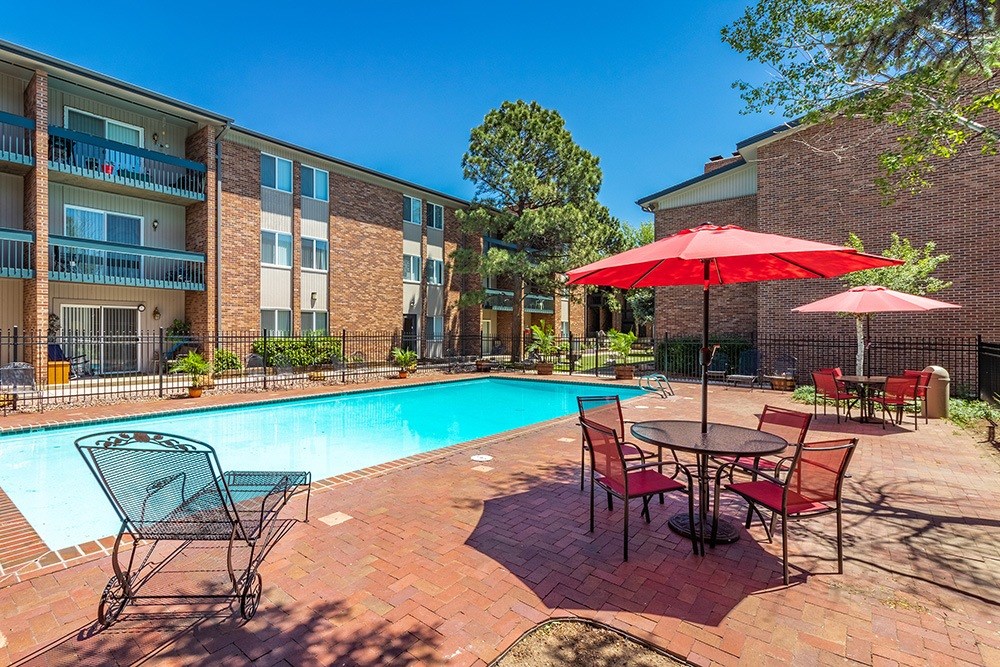 A pool area with a table and chairs and umbrellas.