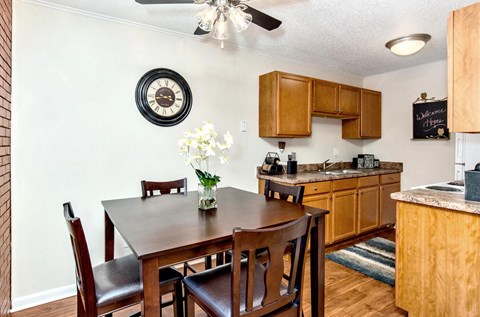 A kitchen with a table and chairs in the foreground and a clock on the wall.