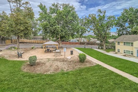A park with a tree, benches, and a playground.