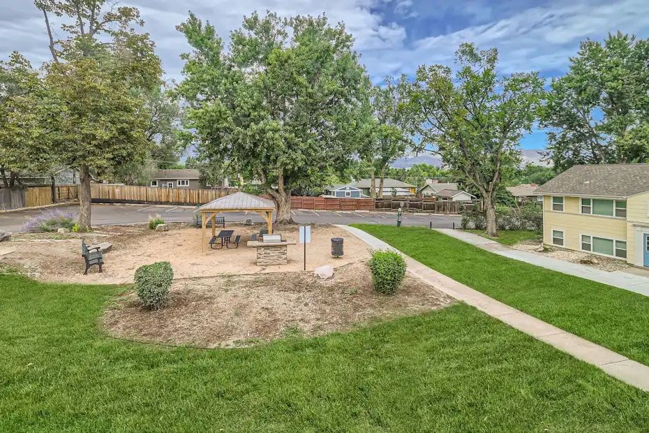 A park with a tree, benches, and a playground.