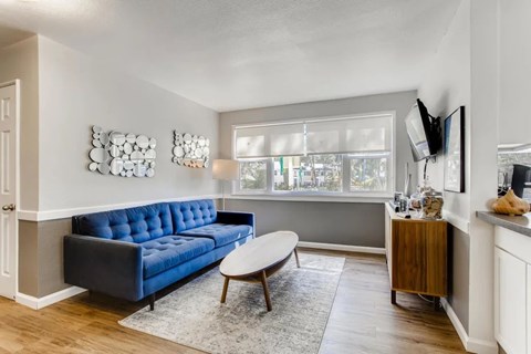 A living room with a blue couch and a wooden coffee table.