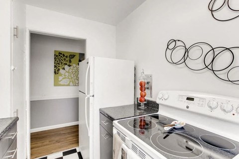 A kitchen with a white stove top oven and a white refrigerator with a green picture in the fridge.