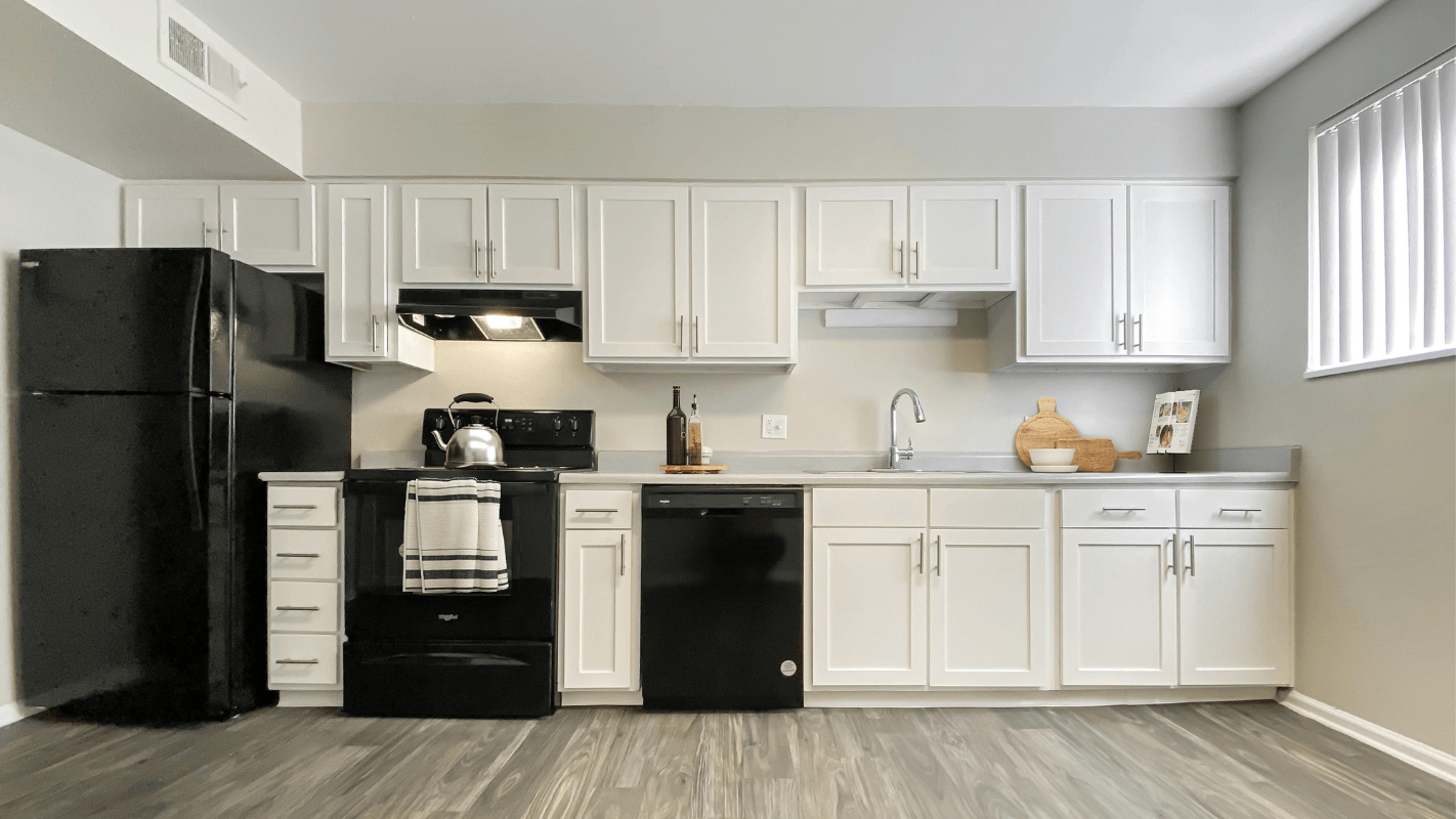 a kitchen with white cabinets and a black refrigerator