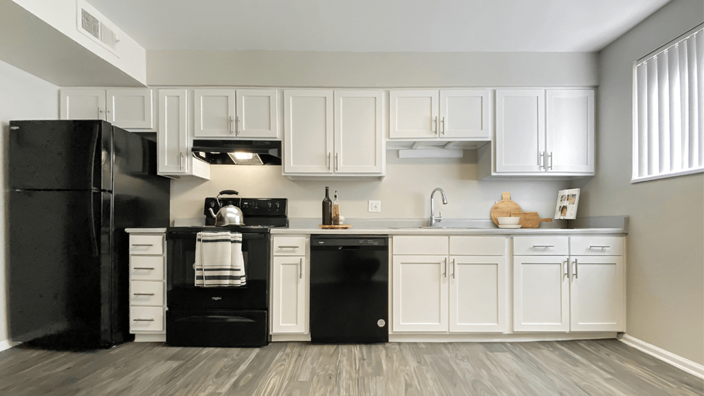 a kitchen with white cabinets and a black refrigerator