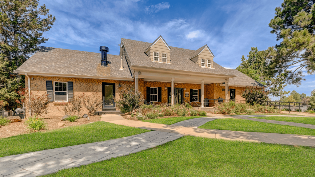 the front of a brick house with a lawn and a pathway