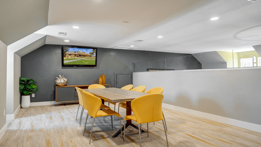 a dining room with a table and chairs and a tv on the wall