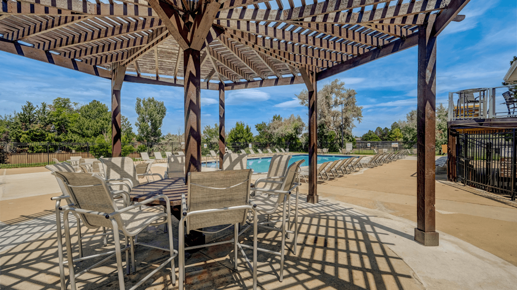 a patio with tables and chairs next to a swimming pool