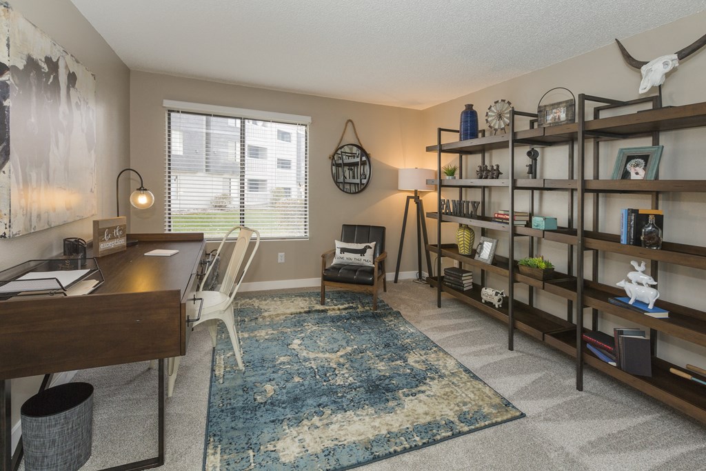 a living room with a desk and a window