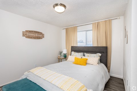 A bedroom with a bed, nightstand, and a sign on the wall.