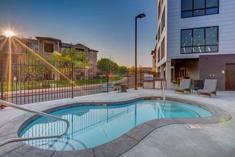 A swimming pool in a residential area with a sunset in the background.