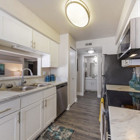 a kitchen with white cabinets and black counter tops and a sink