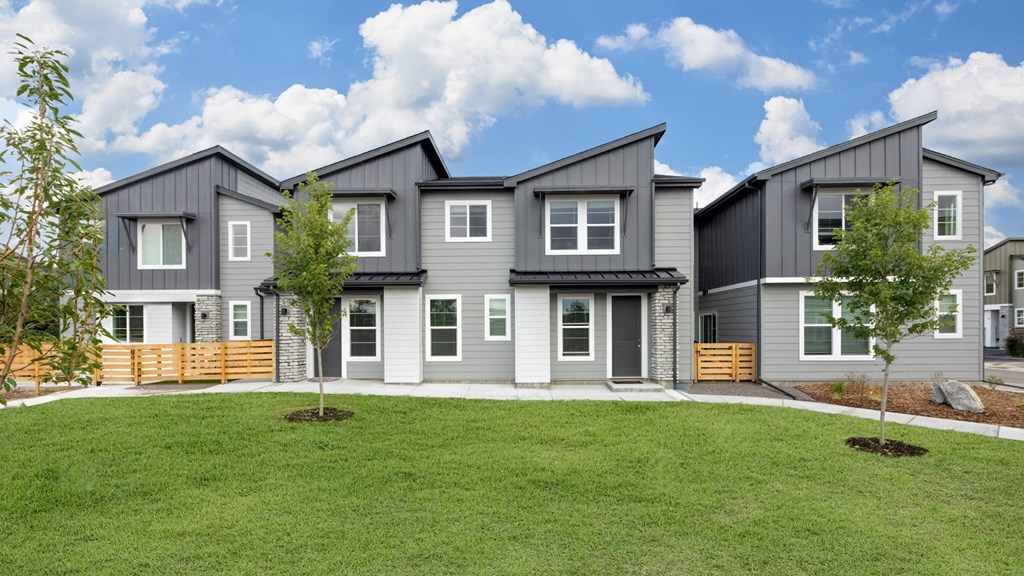 an exterior view of a gray house with a lawn and trees