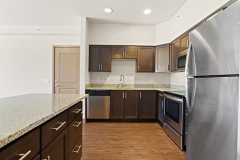 A kitchen with a granite counter top and stainless steel appliances.