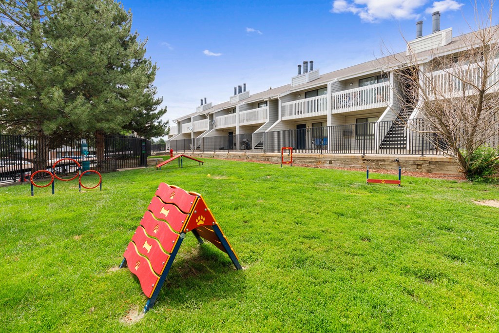 a playground with a red sign in the grass in front of a building