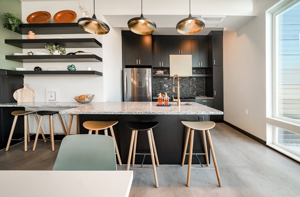 a kitchen with black cabinets and a marble counter top and bar stools