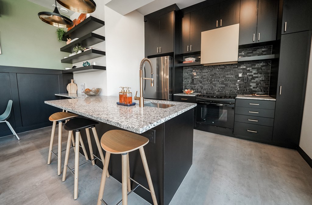 a kitchen with black cabinets and a marble counter top