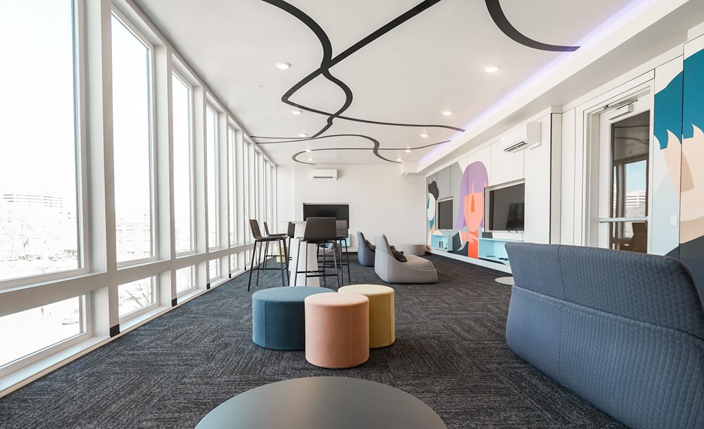 a lounge area with couches chairs and tables and a large window