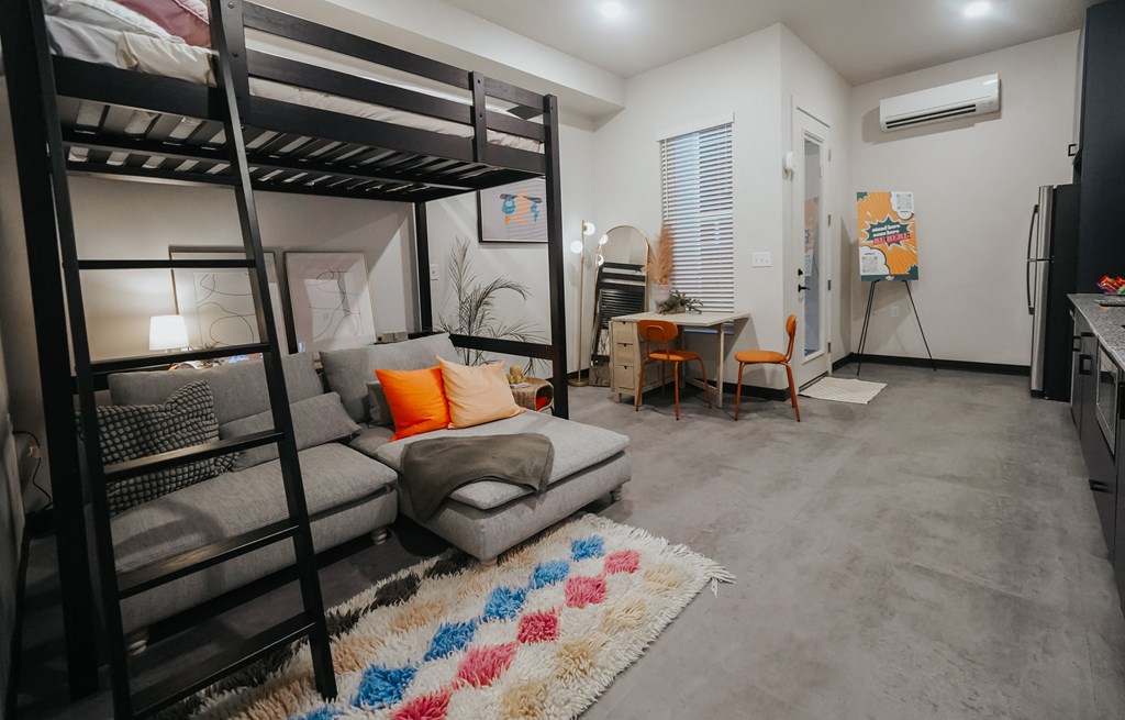 a living room with a bunk bed and a couch and a desk