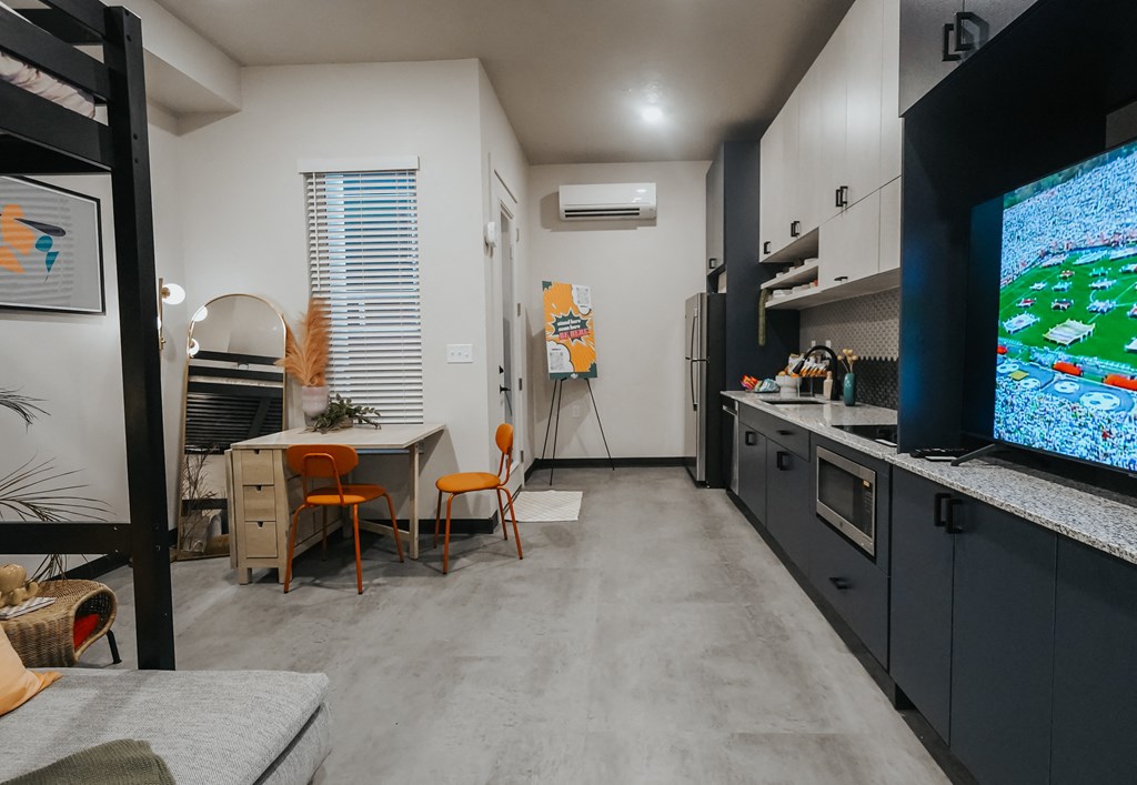 a living room with a tv and a kitchen with a table and chairs