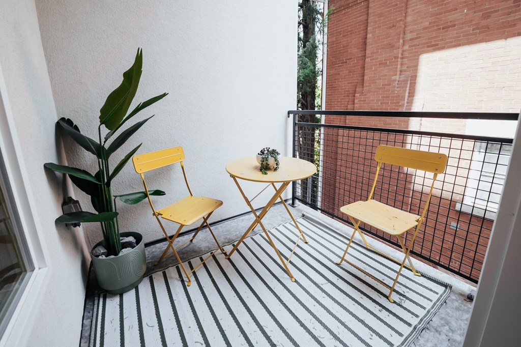 a balcony with two yellow chairs and a small table