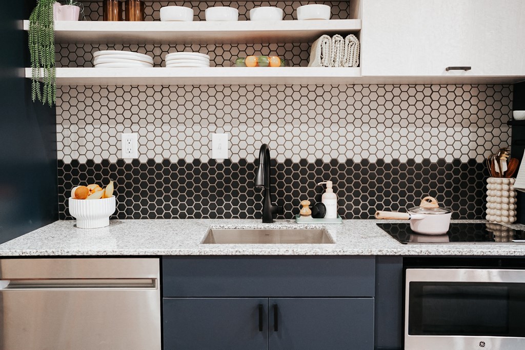 a kitchen with black and white tiles and a sink