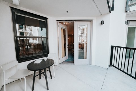 a small balcony with a small table and two chairs and a door to a patio