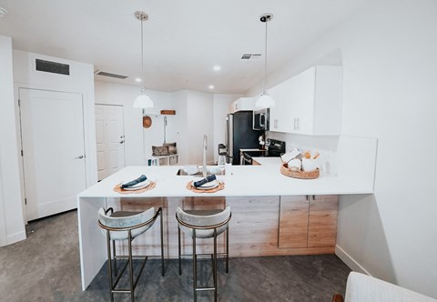 a kitchen with a white counter top and three stools