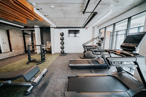a gym with treadmills and other exercise equipment in a building with windows