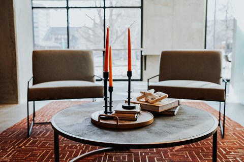 two brown chairs and a coffee table with candles and books