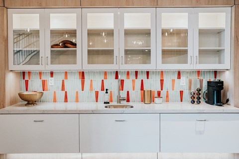 a kitchen with white cabinets and red and white tiles
