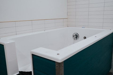 a white bath tub in a white tiled bathroom