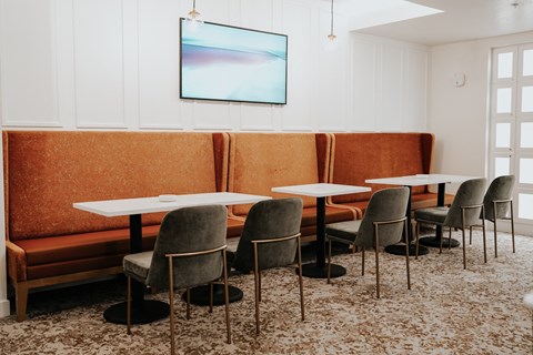 a dining room with tables and chairs and a orange couch