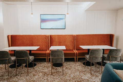 a living room with tables and chairs and a orange couch