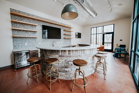 a bar with stools in a room with a fireplace and a television