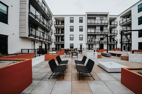 an open courtyard with tables and chairs in front of an apartment building