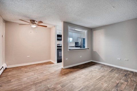 an empty living room with wood floors and a ceiling fan