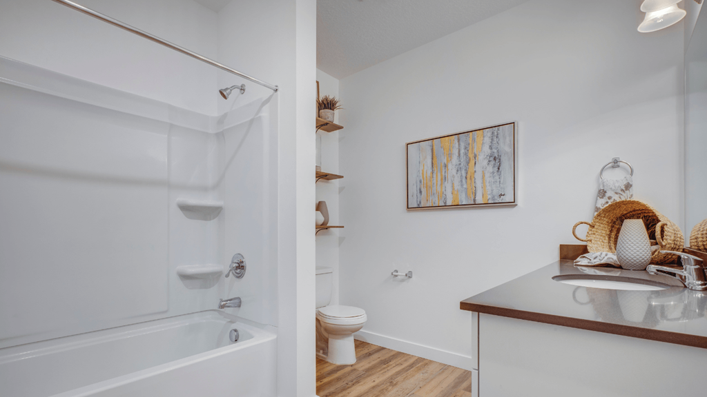 A bathroom with a white tub and a painting on the wall.