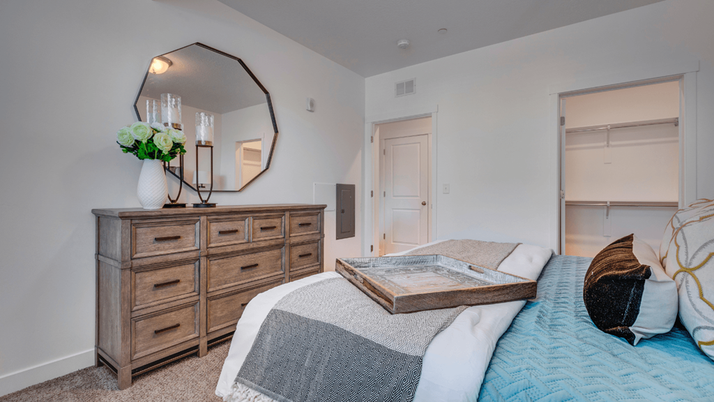 A bedroom with a bed, dresser, and mirror.