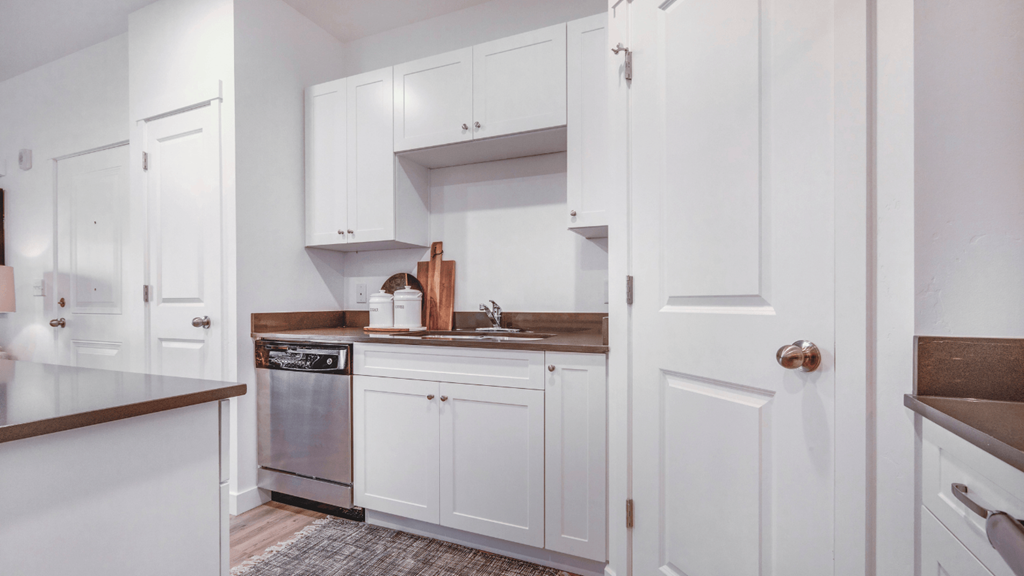 A kitchen with white cabinets and a brown countertop.