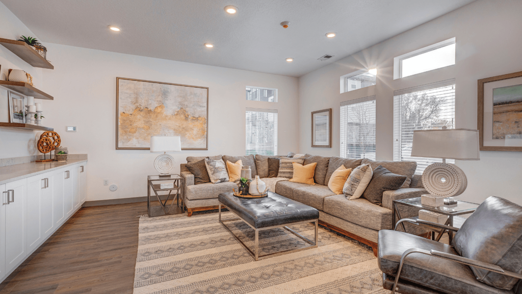 A living room with a brown rug and a grey couch.