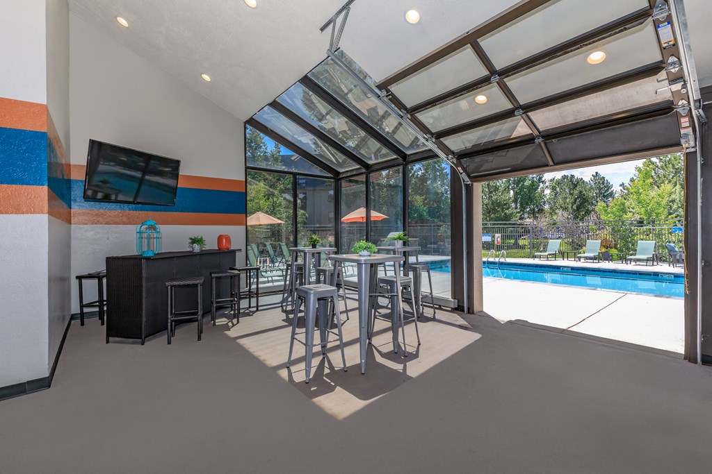 A modern indoor swimming pool area with a glass ceiling and a bar area.