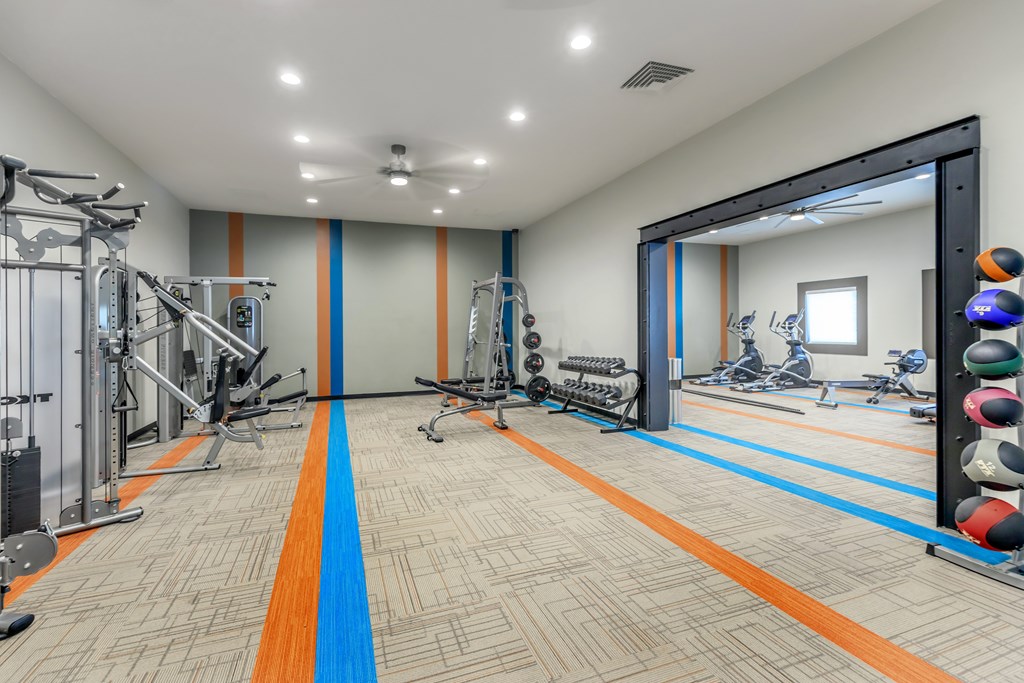 A gym with a variety of equipment including weights and cardio machines.