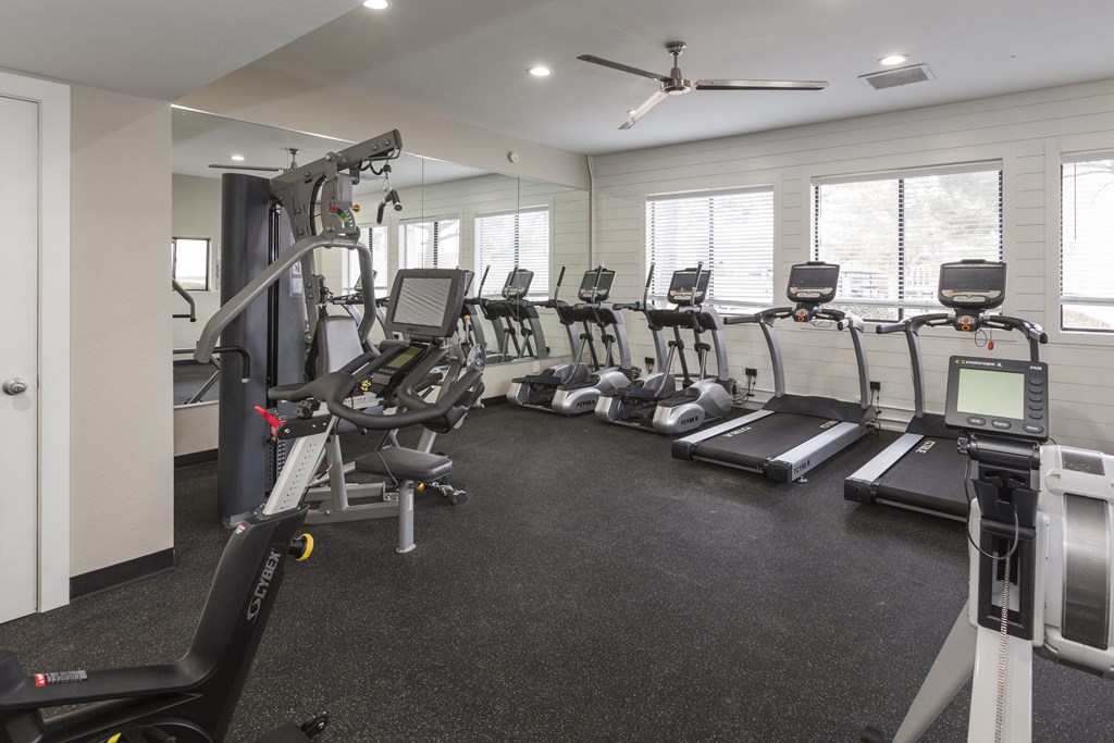 a gym with cardio equipment and windows in a building