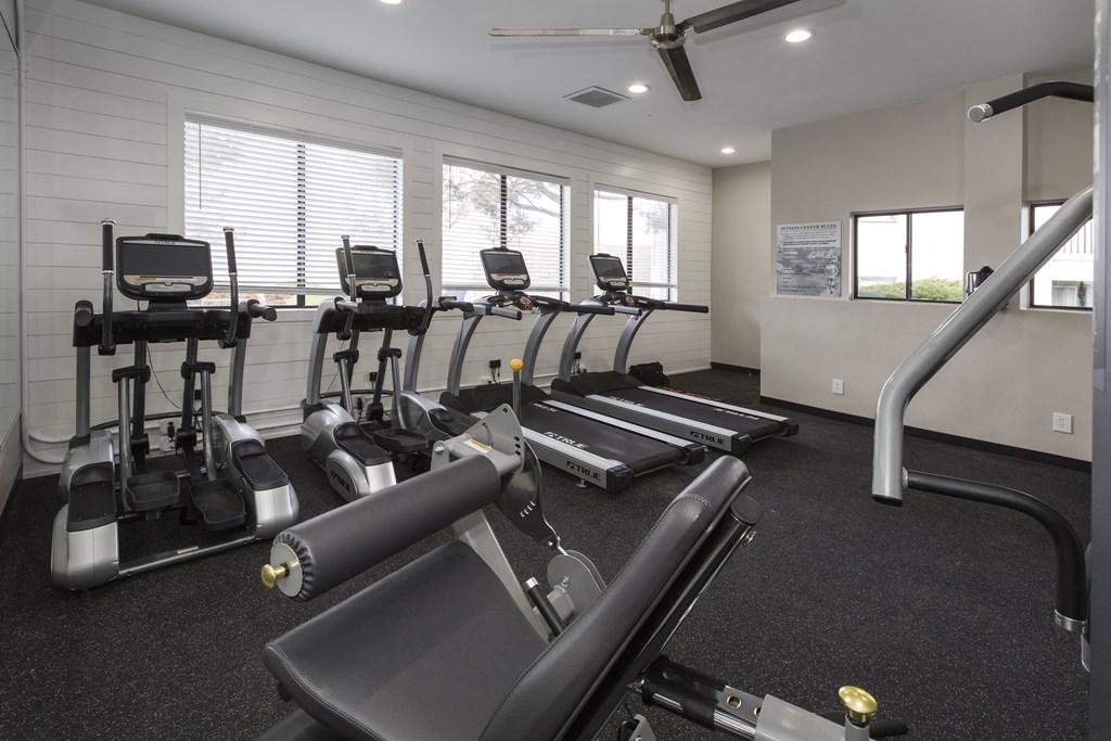 a gym with cardio equipment and windows on the wall