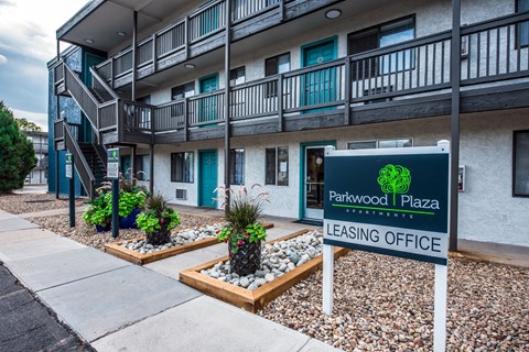 A sign for Parkwood Plaza leasing office in front of a building.