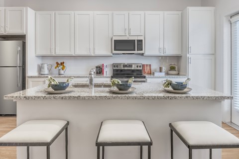 A kitchen with white cabinets and a granite countertop.