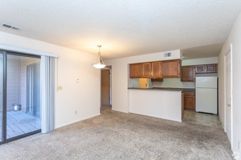 A spacious living room with a kitchen area in the background.